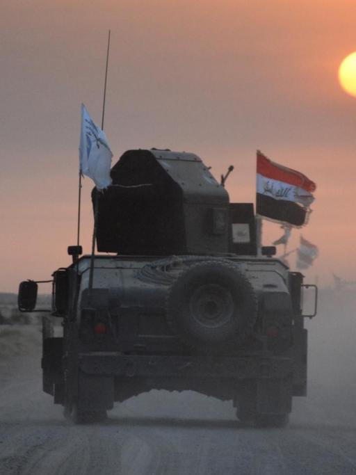 Panzer von irakischen Regierungstruppen fährt auf einer Straße, im Hintergrund Sonnenuntergang.