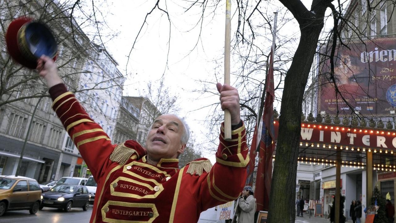 Ein Mann in Portiersuniform winkt am Freitag (09.01.2009) vor dem "Wintergarten" in Berlin vorbeifahrenden Autofahrern mit seiner Mütze zu. Die Mitarbeiter des Varietes in der Potsdamer Straße demonstrierten gegen die Schließung ihrer Einrichtung zum 31. Januar 2009.