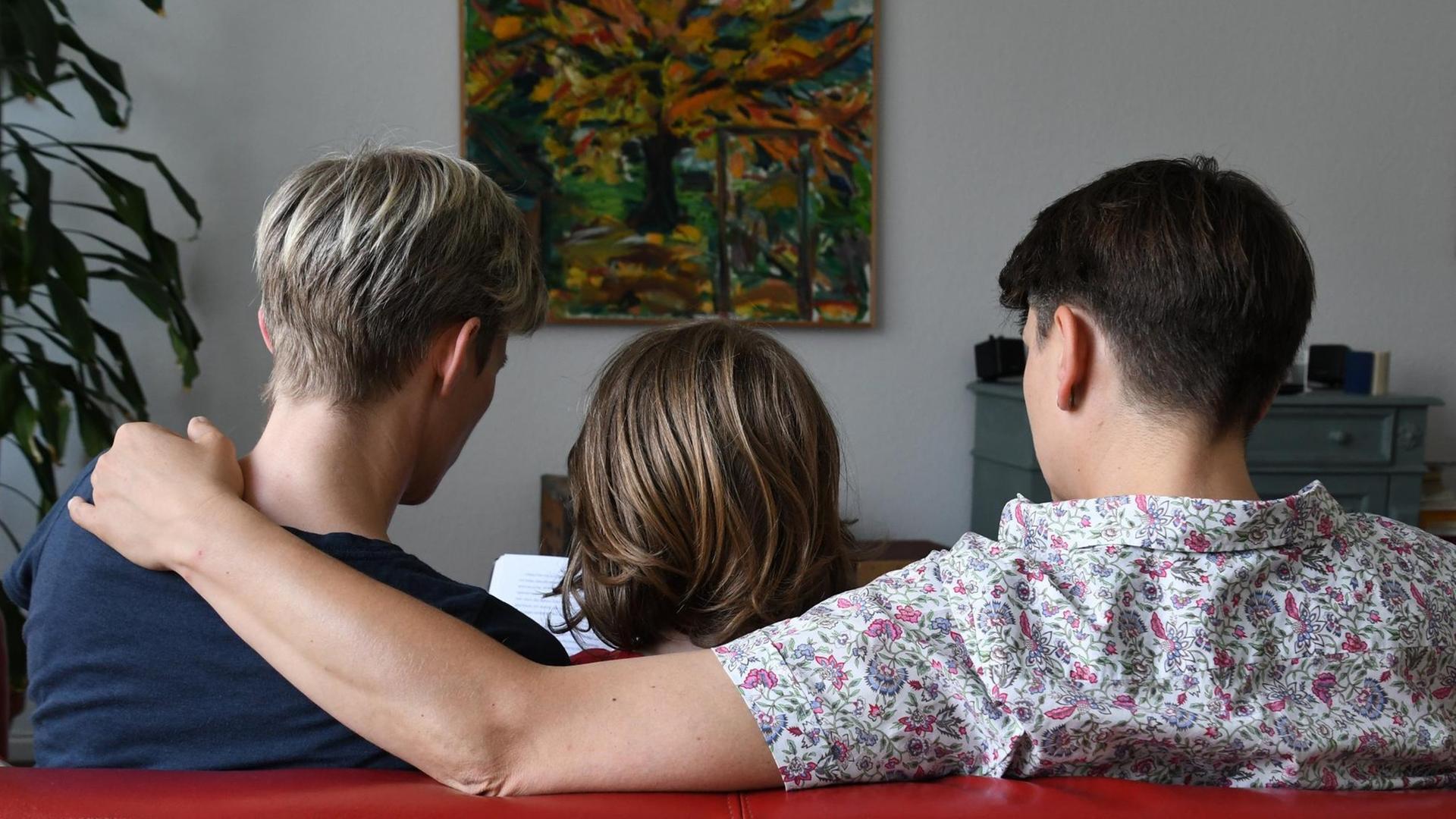 Ein miteinander verpartnertes lesbisches Paar sitzt am 24.06.2016 in Bremen mit seinem Sohn auf dem Sofa und liest in einem Buch.