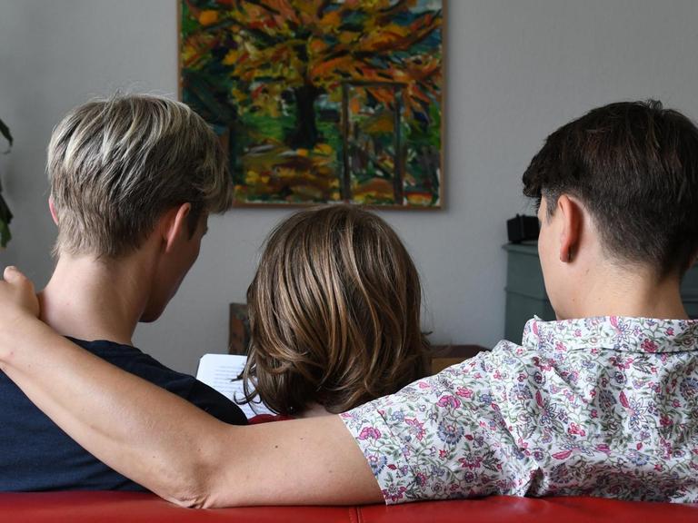 Ein miteinander verpartnertes lesbisches Paar sitzt am 24.06.2016 in Bremen mit seinem Sohn auf dem Sofa und liest in einem Buch.
