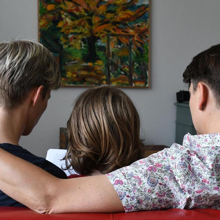 Ein miteinander verpartnertes lesbisches Paar sitzt am 24.06.2016 in Bremen mit seinem Sohn auf dem Sofa und liest in einem Buch. 