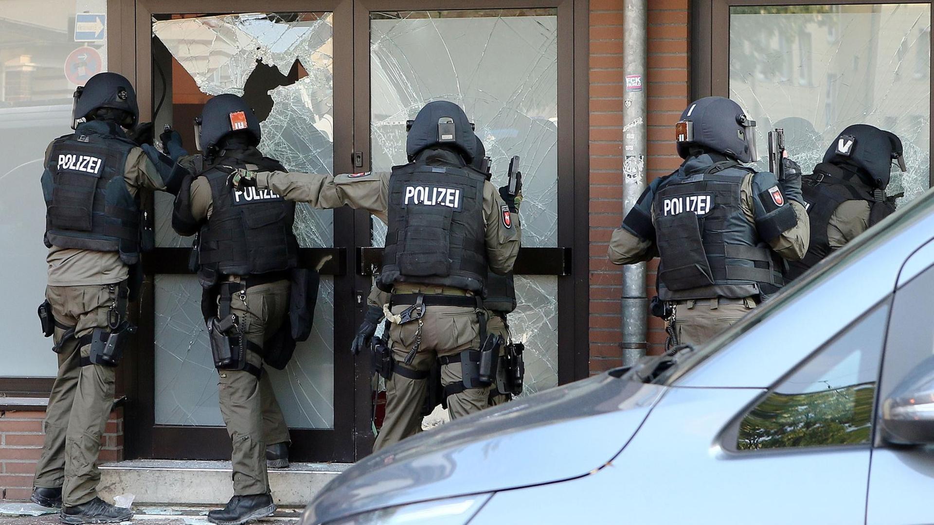 Polizisten stürmen ein Gebäude in Hildesheim, dabei gehen Scheiben zu Bruch.