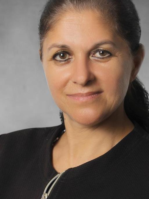 Porträtaufnahme von Meryam Schouler-Ocak vor grau-neutralem Hintergrund.