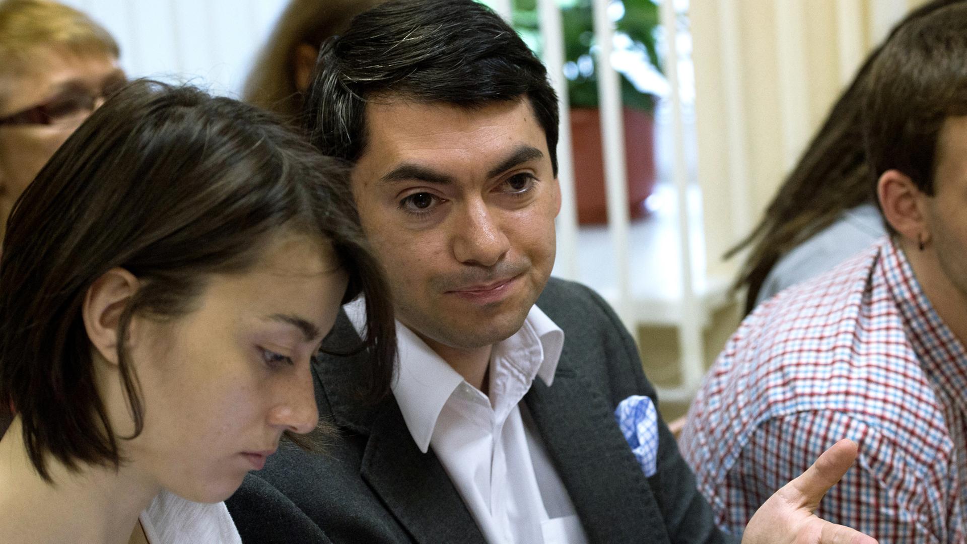 Grigorij Melkonjants, Leiter der NGO "Golos" in Russland, sitzt neben einer Frau, gestikuliert mit einer Hand