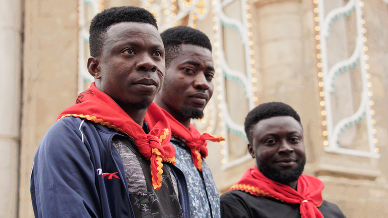 Drei junge Männer aus Ghana. Sie tragen rote Halstücher.