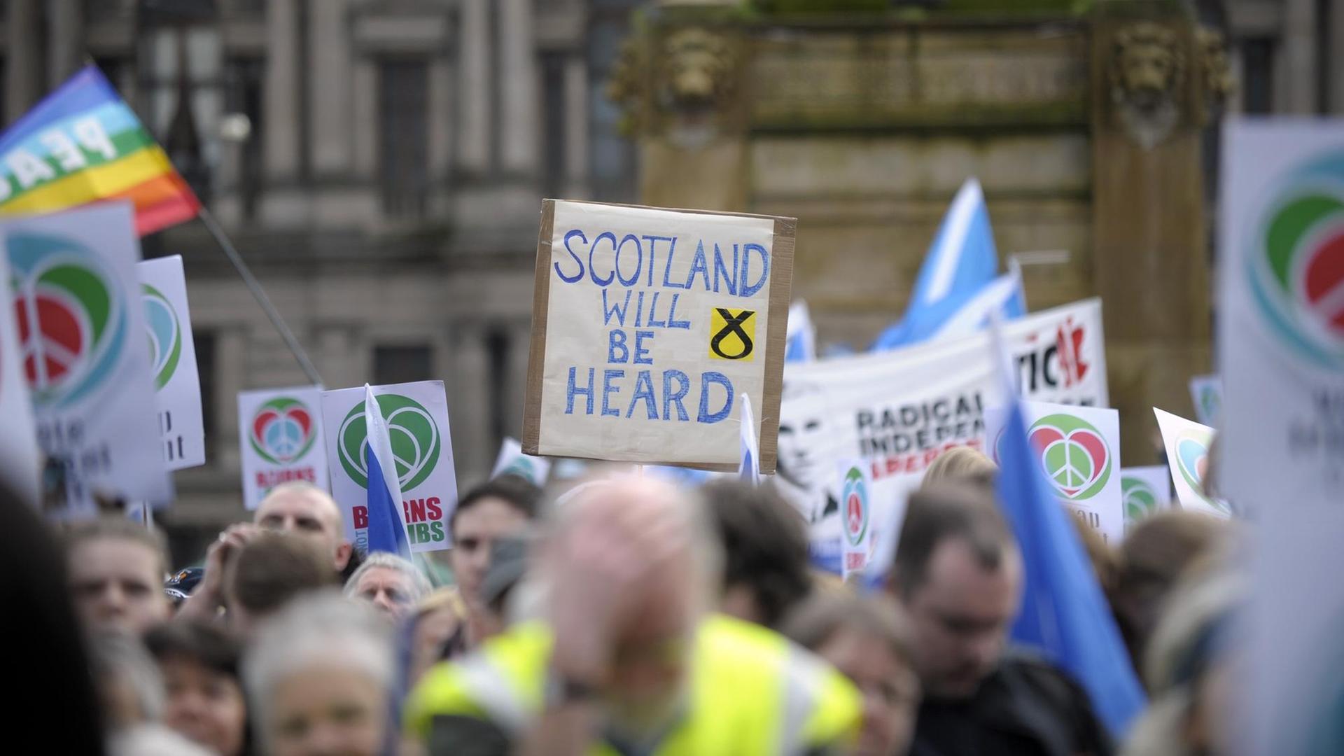 Demonstranten halten Plakate hoch, auf einem ist zu lesen: "Scotland will be heard", zu deutsch: Schottland wird erhört werden.