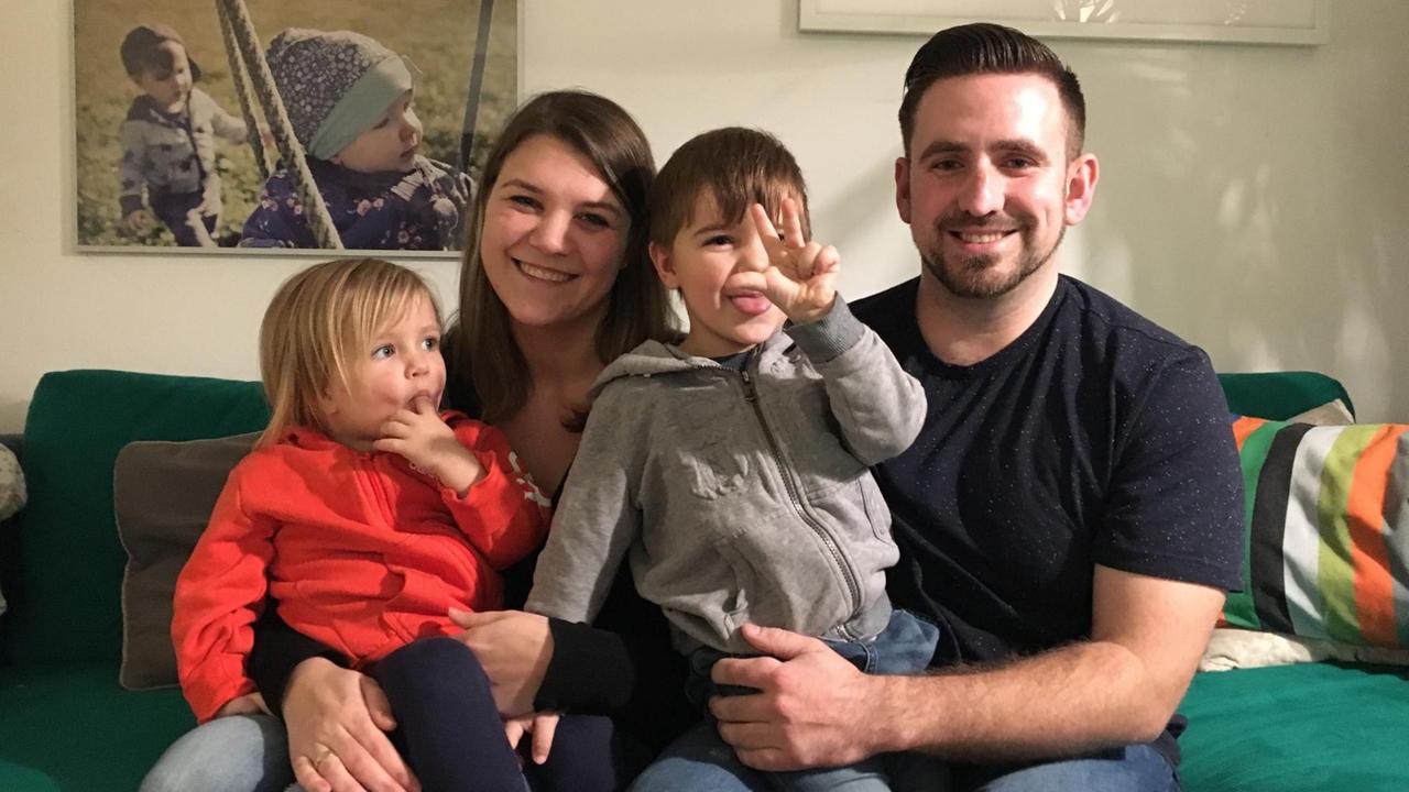 Familie Beyer sitzt auf ihrem Sofa im Wohnzimmer