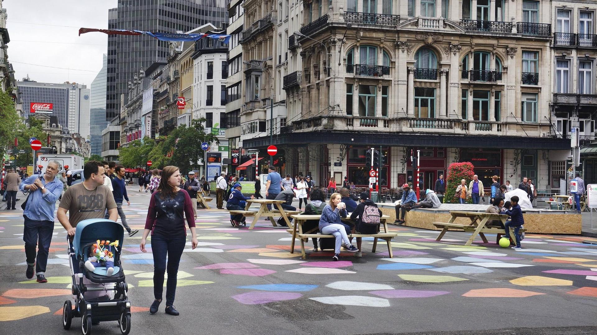 Mehrere Menschen sitzen an Tischen oder gehen über den Boulevard Anspach in Brüssel, der Anfang Juli in eine Fußgängerzone umgewandelt worden ist.