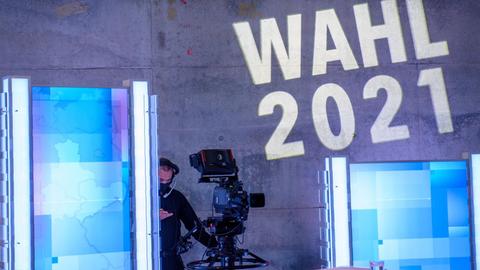 Eine Kamera steht in der MDR-Wahlarena im MDR-Landesfunkhaus unter den Worten "Wahl 2021" die an die Wand projiziert sind.
