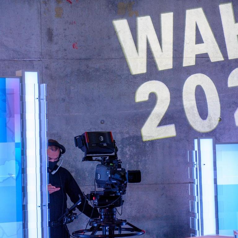Eine Kamera steht in der MDR-Wahlarena im MDR-Landesfunkhaus unter den Worten "Wahl 2021" die an die Wand projiziert sind.