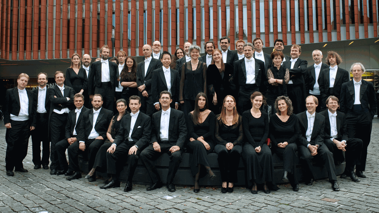 Die Musikerinnen und Musiker des Orchesters Anima Eterna Brugge stehen in einem gepflasterten Innenhof
