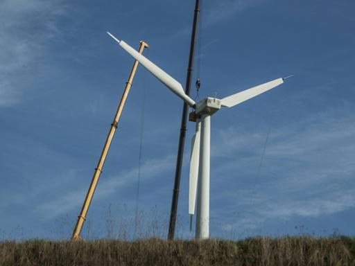 Zwei große Kräne stehen neben einem Windrad, das abgebaut werden soll