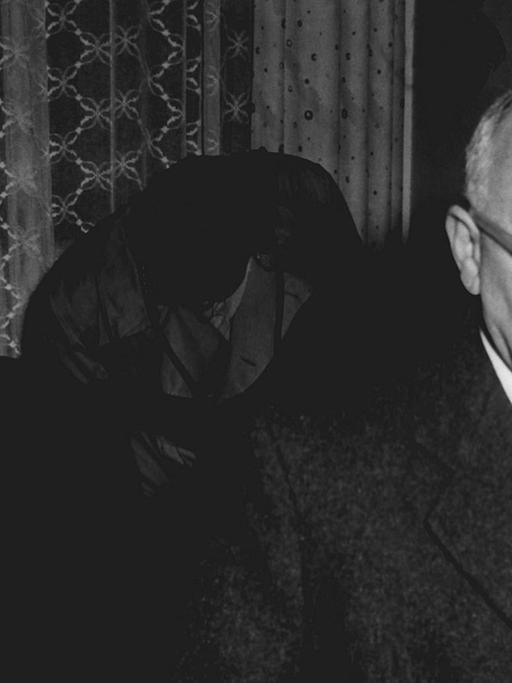 Eine schwarz-weiß-Fotografie zeigt Bertolt Brecht und Johannes R. Becher, wie sie 1954 gemeinsam durch ein Hotelzimmer laufen.
