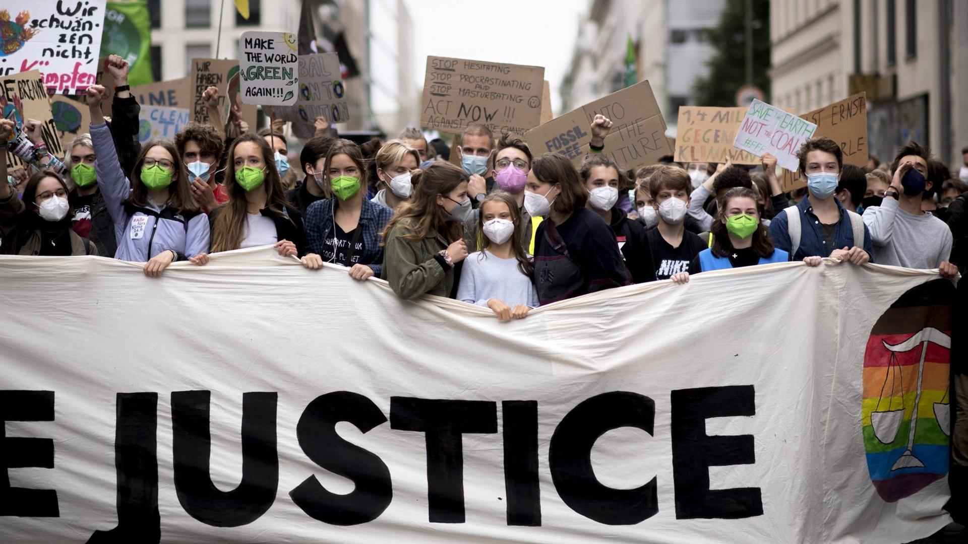 In Berlin demonstrieren viele junge Menschen gegen die Klimakrise. In der ersten Reihe steht Greta Thunberg hinter einem Banner mit der Aufschruft "Justice".