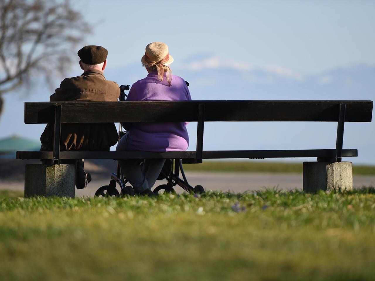 Zwei Senioren sitzen an der Uferpromenade in Langenargen (Baden-Württemberg) auf einer Parkbank.