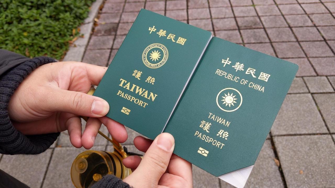 Zwei Hände halten taiwanesische Reisepässe in altem und neuem Design nebeneinander.