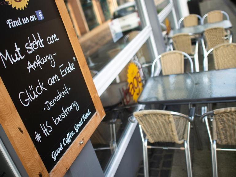 Ein Schild mit der Aufschrift "Mut steht am Anfang - Glück am Ende. #HSbestrong" steht an einem Café in der Fußgängerzone in Heinsberg.