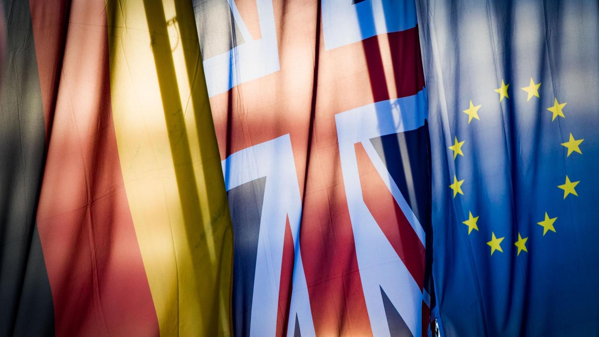Eine deutsche, eine britische und eine europäische Flagge hängen nebeneinander.