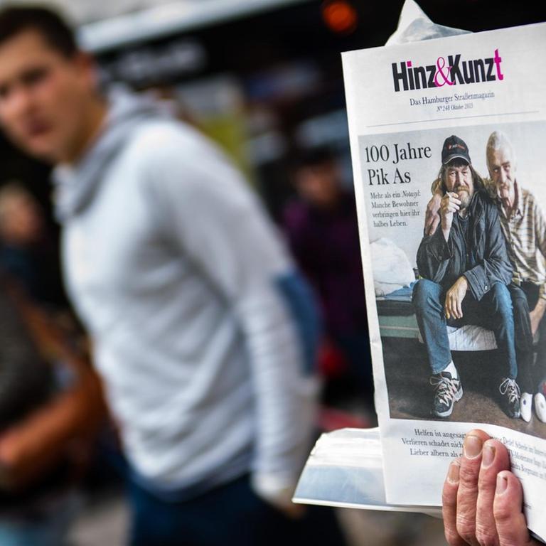 Der ehemalige Obdachlose Klaus hält vor einem Kaufhaus in Hamburg einen Stapel des Straßenmagazins "Hinz & Kunzt" in der Hand. 