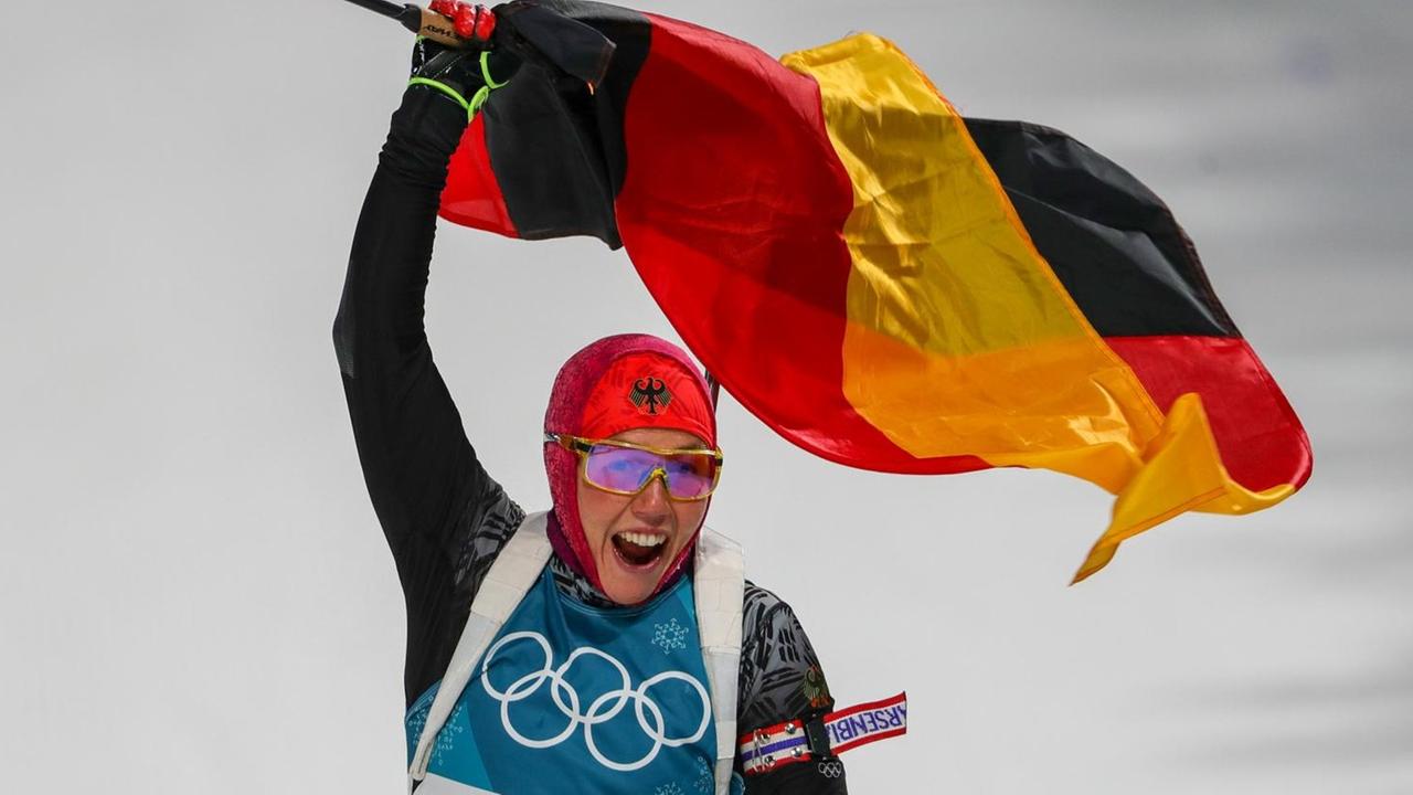 Biathletin Laura Dahlmeier feiert mit der deutschen Fahne in der Hand ihren Olympiasieg im Verfolgungsrennen in Pyeongchang
