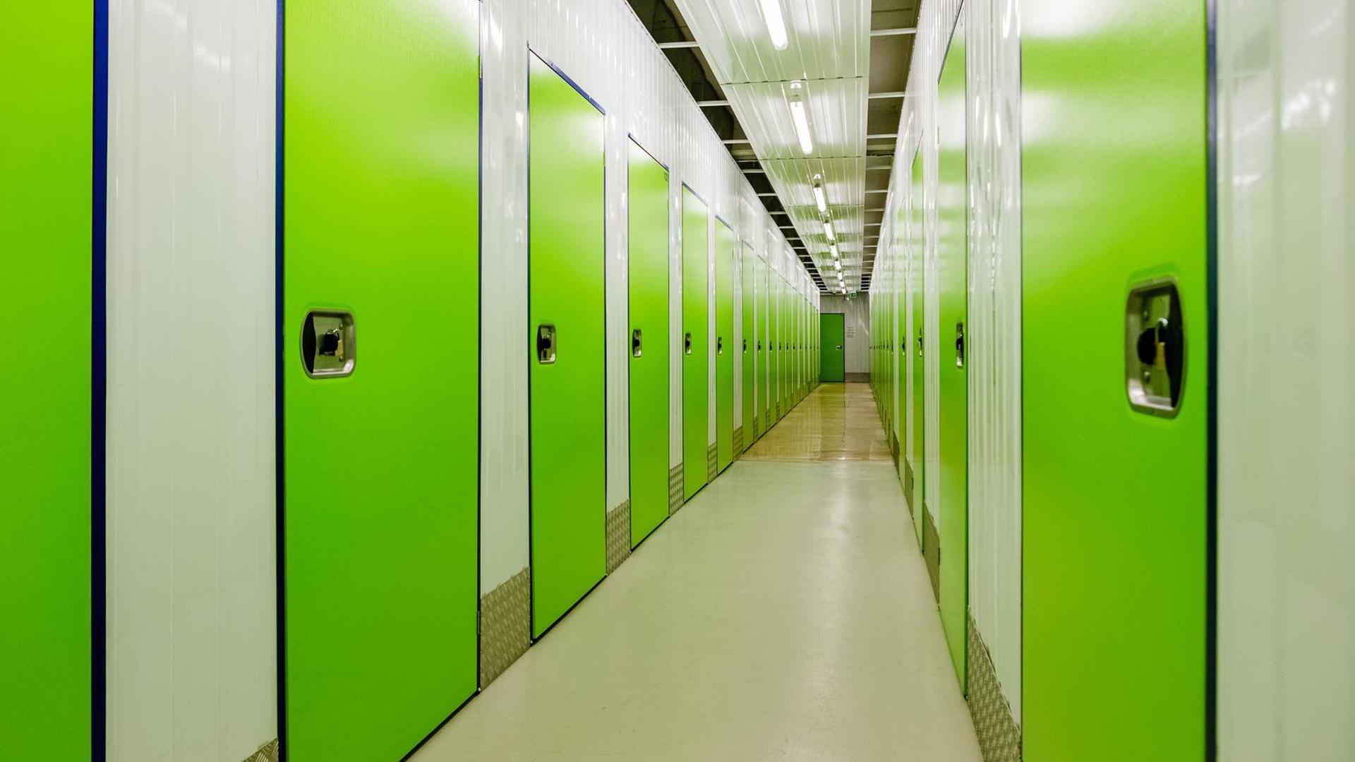Ein langer Gang mit neon-grünen Türen. Dahinter befinden sich Boxen eines Selfstorage-Lagerhauses.