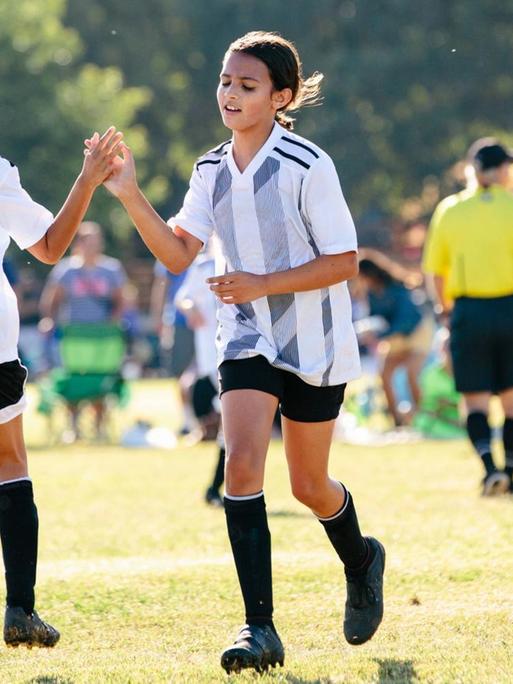 Mädchen eines Fußballteams klatschen sich nach einem Tor ab