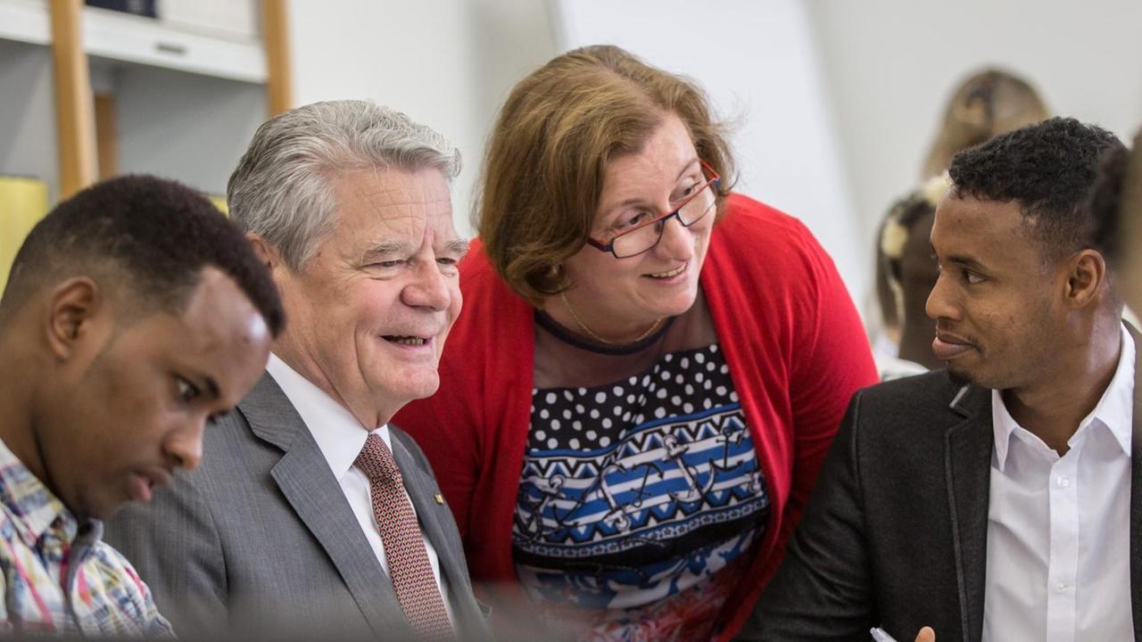 Bundespräsident Joachim Gauck(2.v.l.) und Schulleiterin Annette Greilich (M) sprechen am 17.06.2015 in Gießen (Hessen) an der beruflichen Friedrich-Feld-Schule mit jugendlichen Flüchtlingen, die hier unter Anleitung von Berufsfachschülern und Lehrern im Rahmen der Initiative "DaZuLERNEN" Deutschunterricht erhalten.