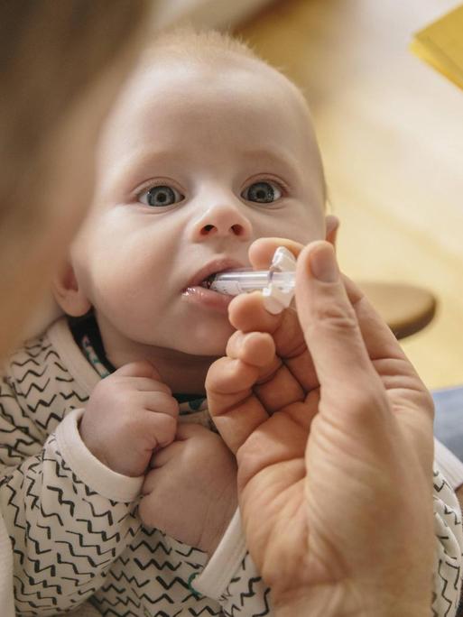 Ein drei Monate altes Baby erhält eine orale Impfung.