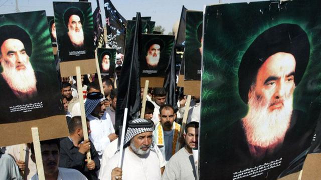 Irakische Schiiten tragen vor sich Plakate von Großayatollah Ali al-Sistani; er tritt selbst nur äußerst selten öffentlich auf.