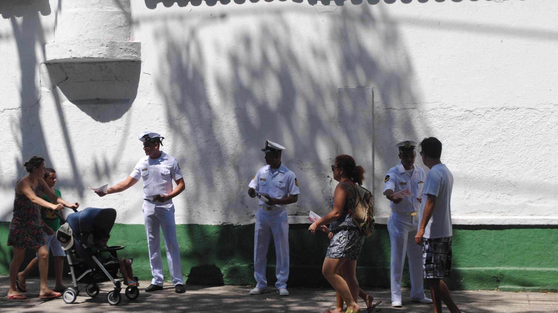Angehörige der brasilianischen Marine verteilen auf der Straße Zettel an Passanten.