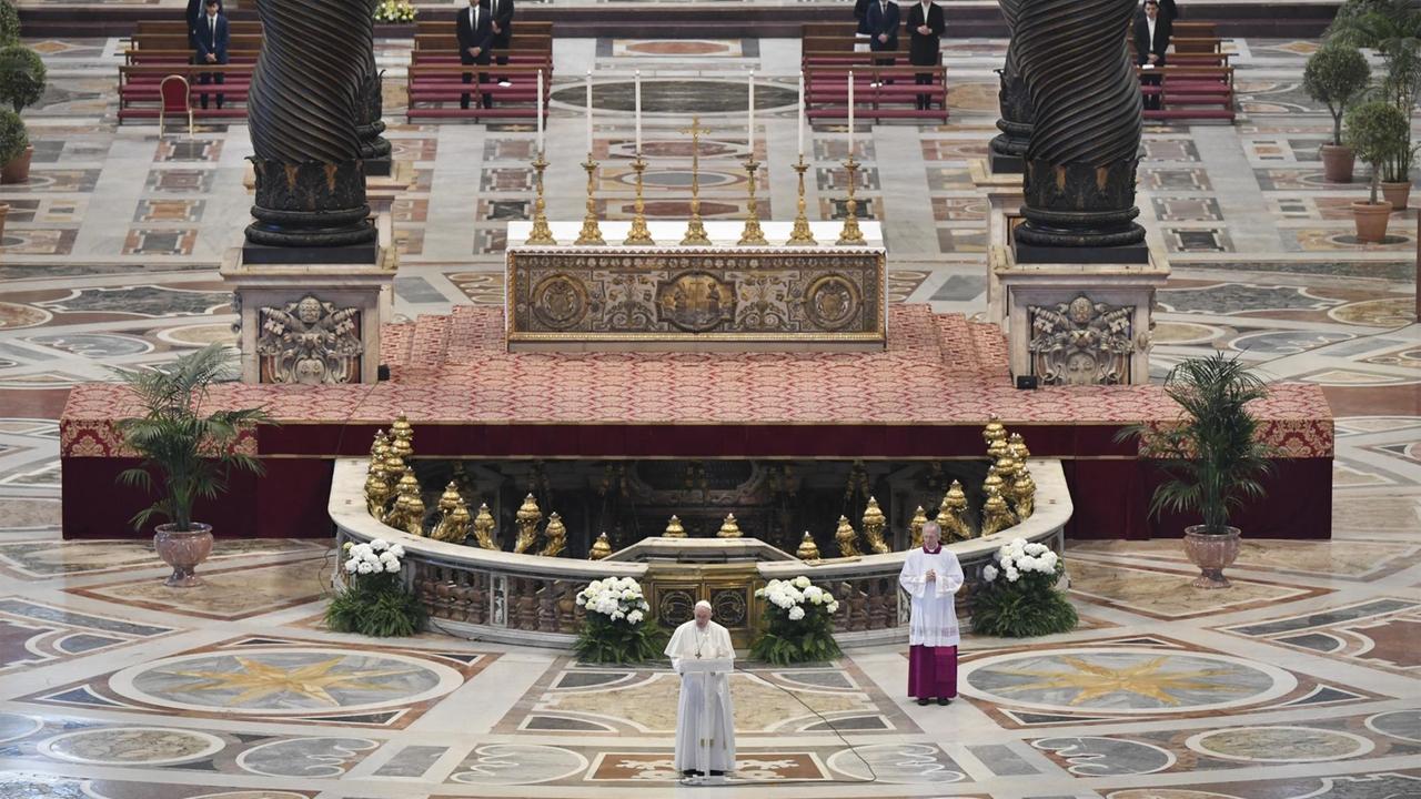 Papst Franziskus steht an einem Pult in einem fast menschenleeren Petersdom.