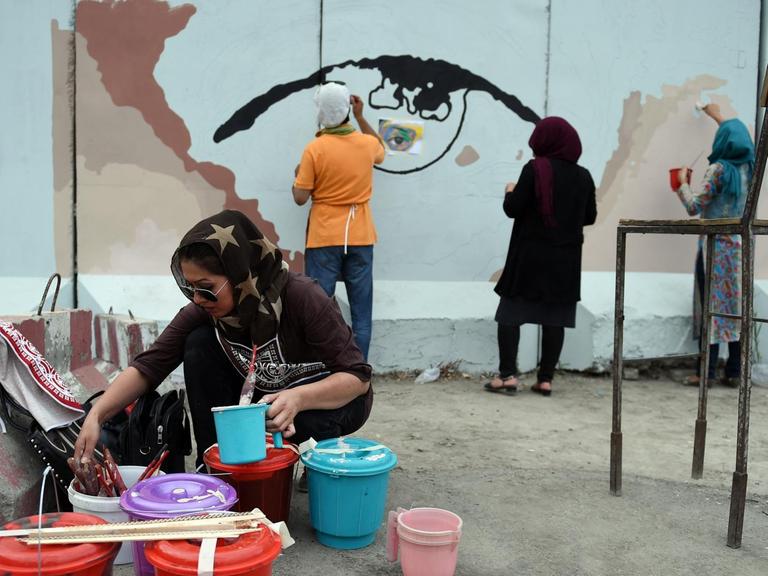 Auf dm Foto vom 21. Juli 2015 malen afghanische Künstlerinnen und Freiwillige das Motiv der Augen einer Frau auf eine Sperrmauer am Präsidentenpalast in Kabul.