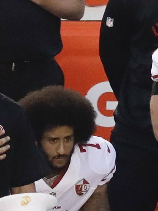 Der Quarterback der San Francisco 49ers, Colin Kaepernick (Mitte), kniet beim Abspielen der Nationalhymne.