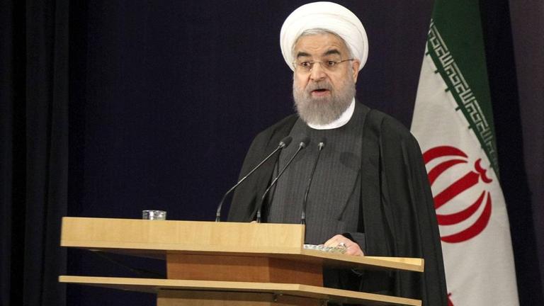 Irans Präsident Hassan Ruhani steht an einem Rednerpult und spricht.