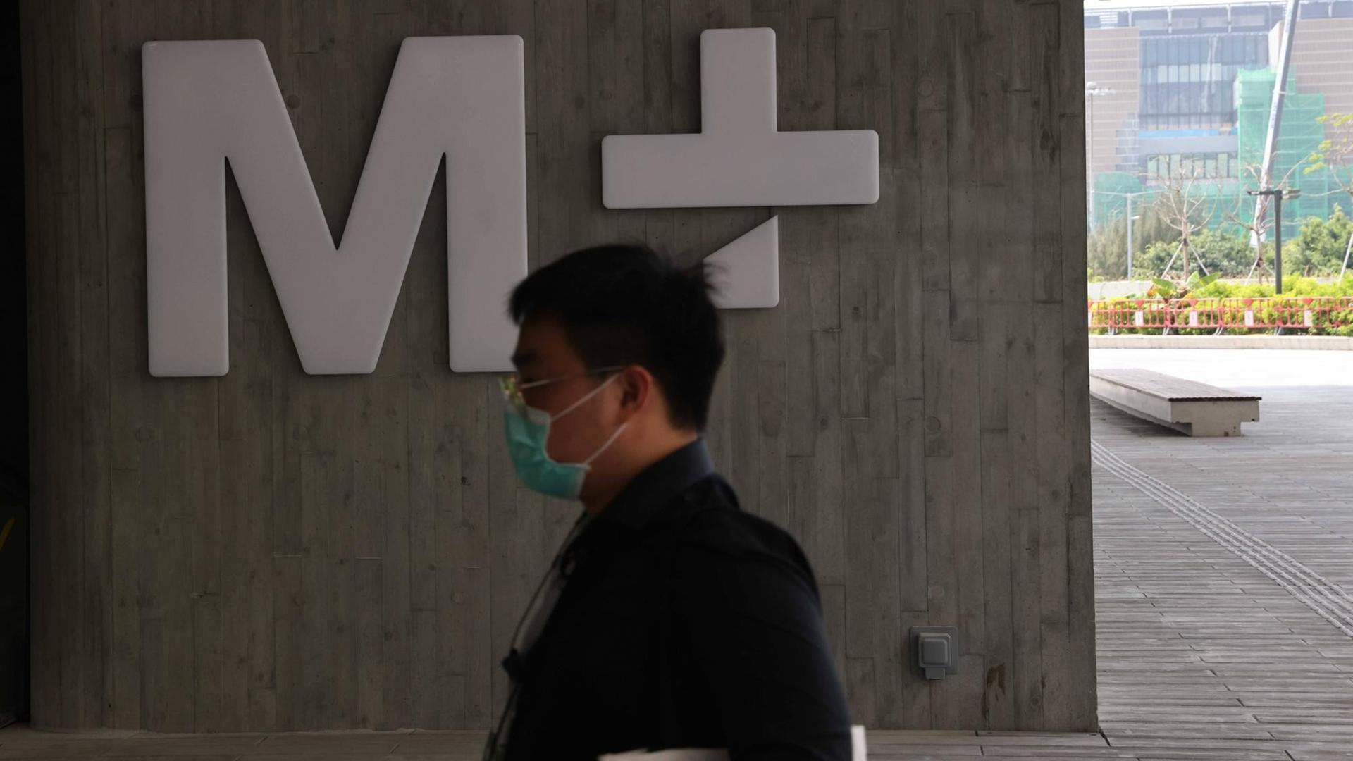 Während des Presserundgangs geht jemand im Eingangsbereich des Museums am M+-Logo vorbei.