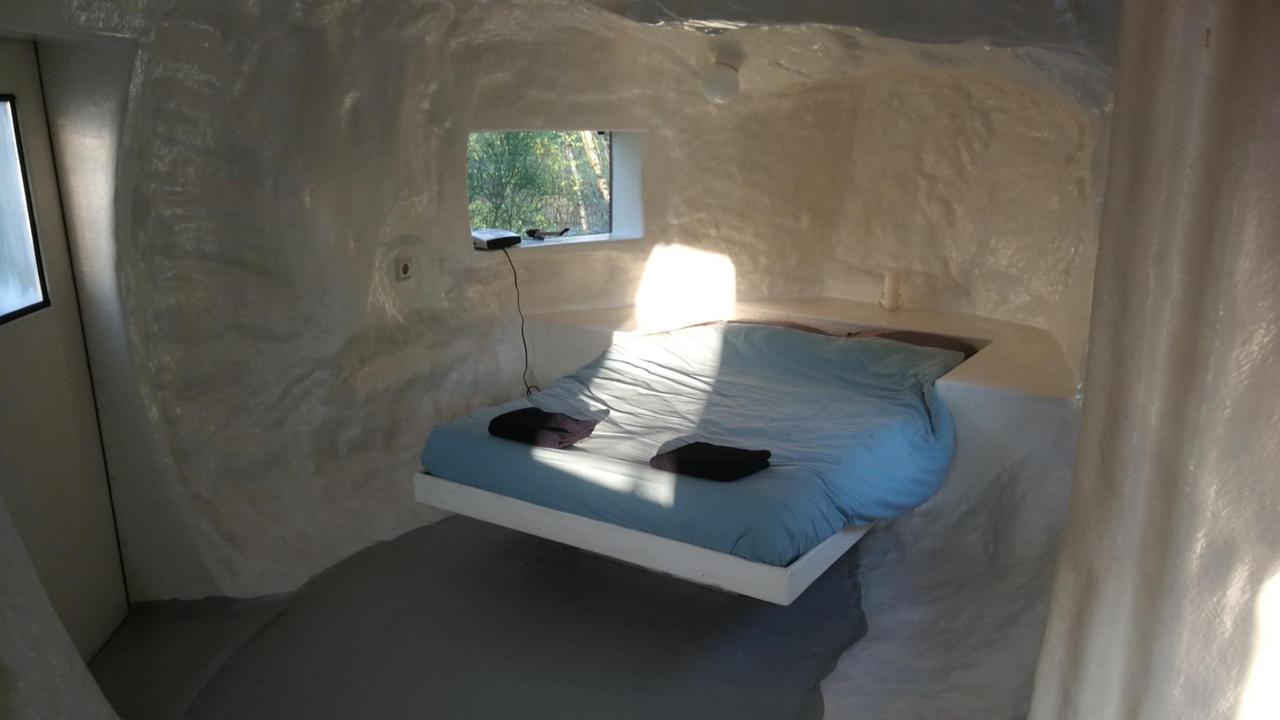 Spartanische Einrichtung mit Bett und weißen Wänden: Das Werk "CasAnus" von Joep van Lieshout auf dem Gelände der Verbeke Foundation