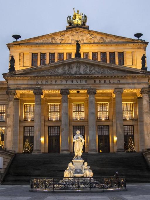 Blick auf das festliche erleuchtete, historische Konzerthaus mit Schillerdenkmal in der Dämmerung.