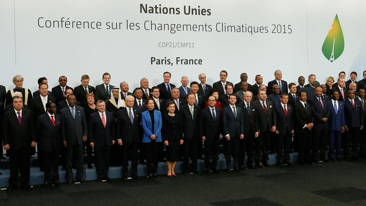 Die Staats- und Regierungschefs stehen neben- und hintereinander vor einem  weißen Wand mit dem Schriftzug der Klimakonferenz in französischer Sprache.