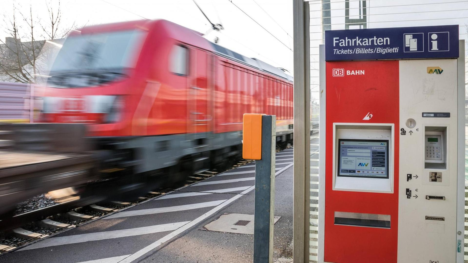 Güterzug mit Waggons fährt an Bahnsteig vorbei mit Bewegungsunschärfe, daneben Fahrkartenautomat Bahnhof Langweid in Bayern *** Freight train with waggons drives past platform with motion blur next to ticket machine station Langweid in Bavaria