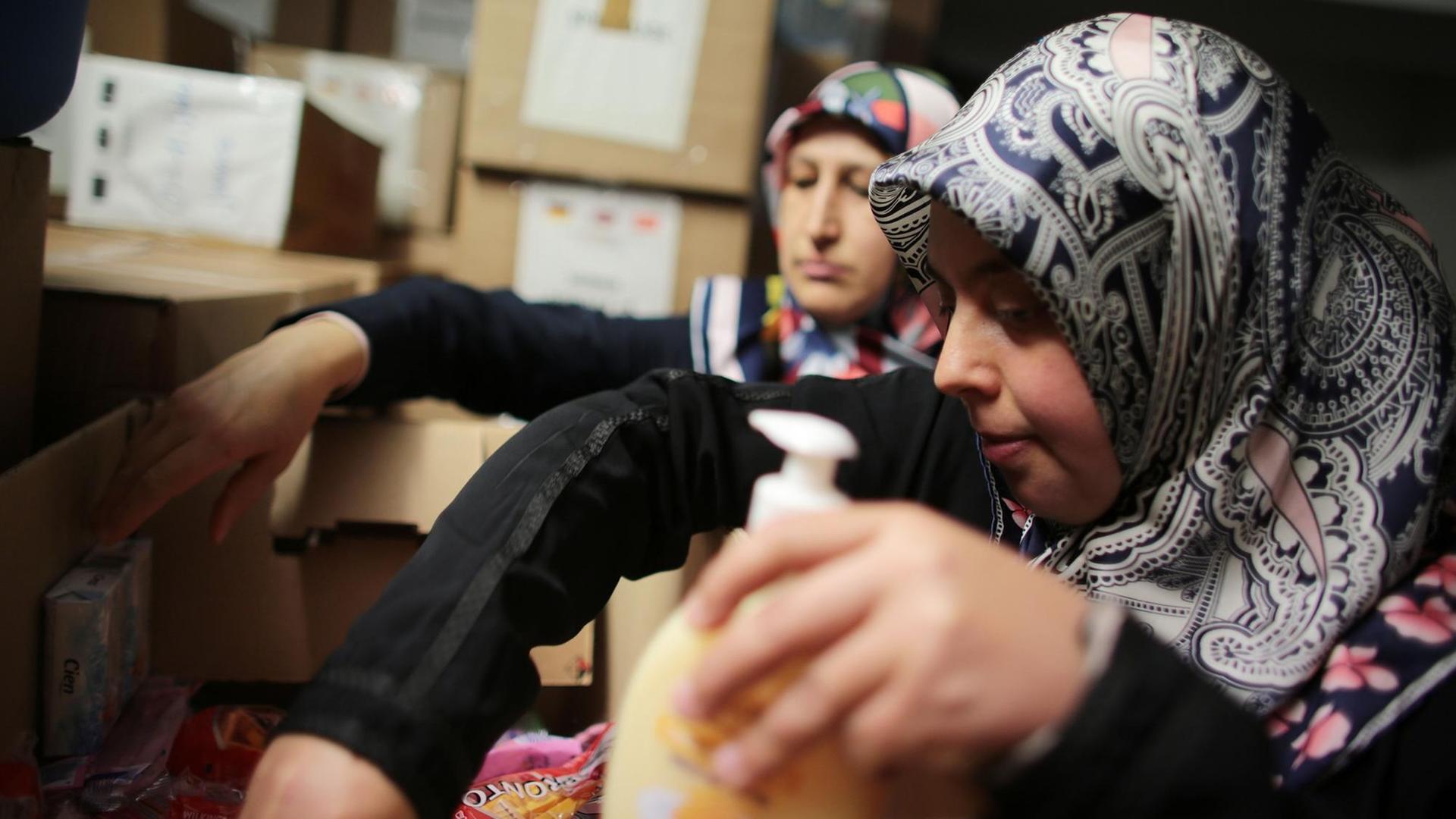 Die türkischen Frauen Sevgül Tunc (r) und Hayriye Aydin sortieren in einer Kölner Moschee Spenden für Flüchtlinge.