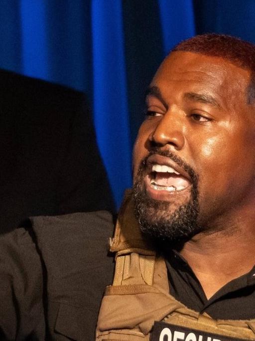 Der US-amerikanische Rapper Kanye West begrüßt in einer Weste der Security seine Anhänger in South Carolina bei einer Veranstaltung im Rahmen der anstehenden Präsidentschaftswahlen 2020