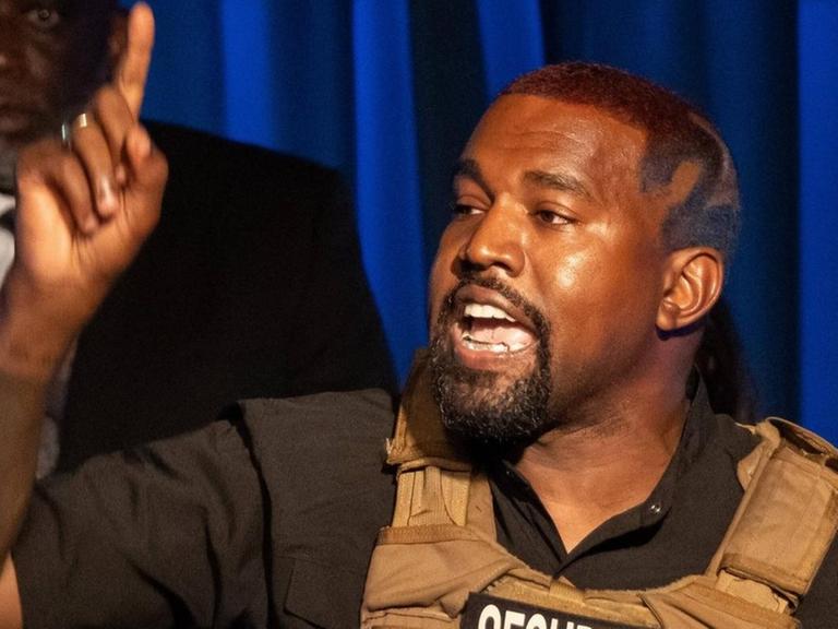 Der US-amerikanische Rapper Kanye West begrüßt in einer Weste der Security seine Anhänger in South Carolina bei einer Veranstaltung im Rahmen der anstehenden Präsidentschaftswahlen 2020