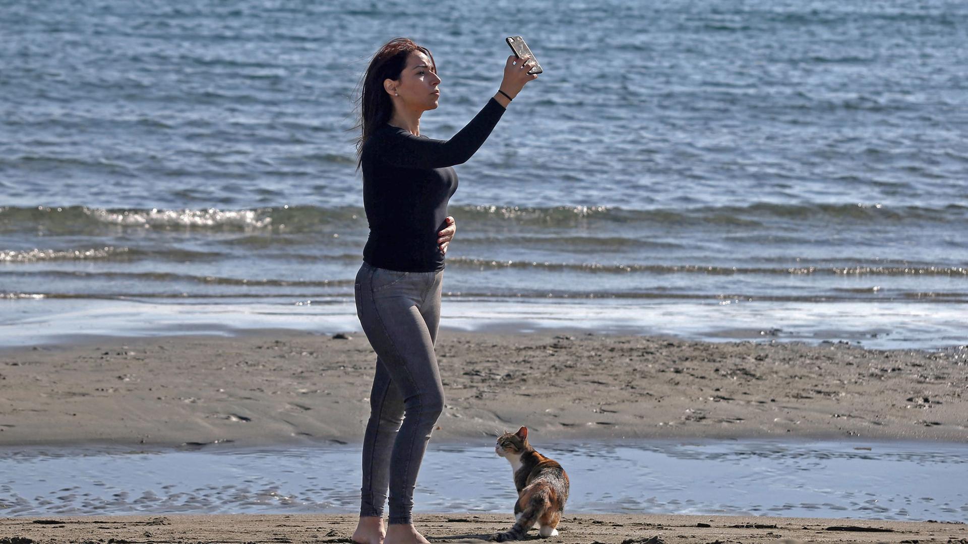 Eine Frau schießt am Strand ein Selfie.