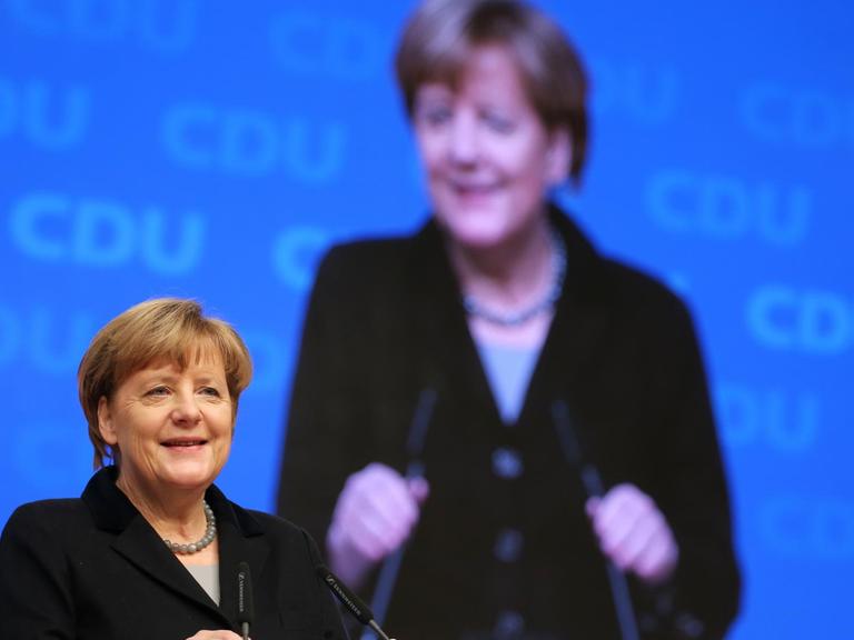Die CDU-Bundesvorsitzende und Bundeskanzlerin Angela Merkel begrüßt am 14.12.2015 in Karlsruhe (Baden-Württemberg) beim Beginn des Bundesparteitages die Delegierten.