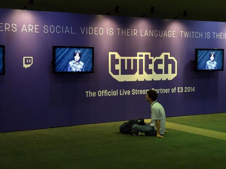 Ein junger Mann sitzt vor Bildschirmen der Streamingplatform Twitch.