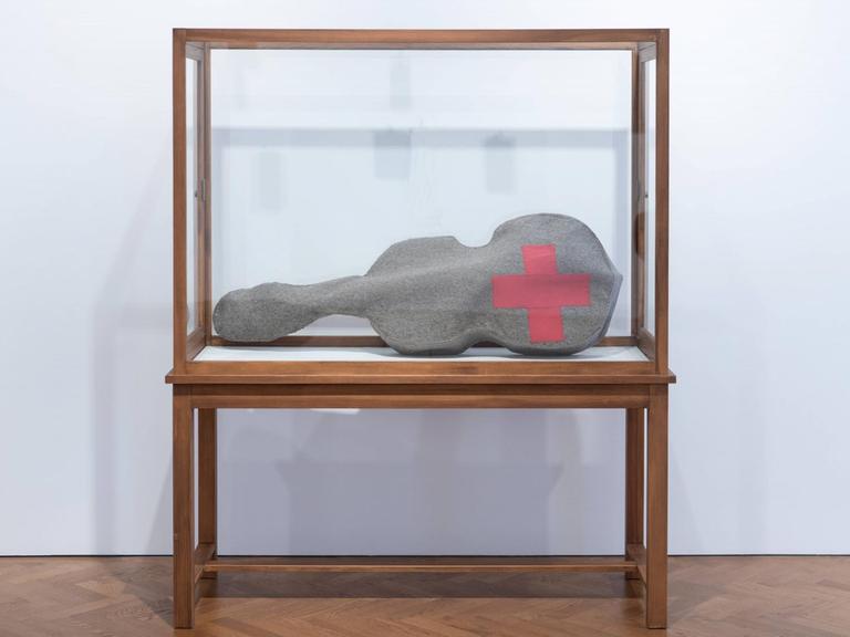 Beuys Arbeit 'Infiltration - Homogen für Cello' besteht aus einer gefilzten Cello-Tasche mit einem roten Kreuz. Hier zu sehen in einer Glasvitrine während der Ausstellung "The Stag Monuments" in der Galerie Thaddaeus Ropac in London, kuratiert von Norman Rosenthal.