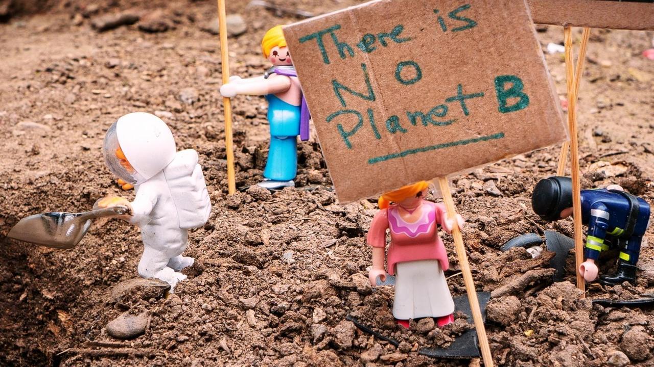 Playmobilfiguren mit einem Schild "There is no Planet B.".