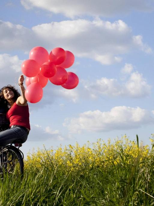 Junges Paar auf einem Fahrrad mit Luftballons