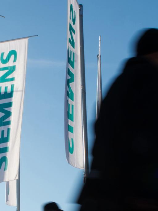 Siemens-Flaggen im Wind, davor laufen Menschen