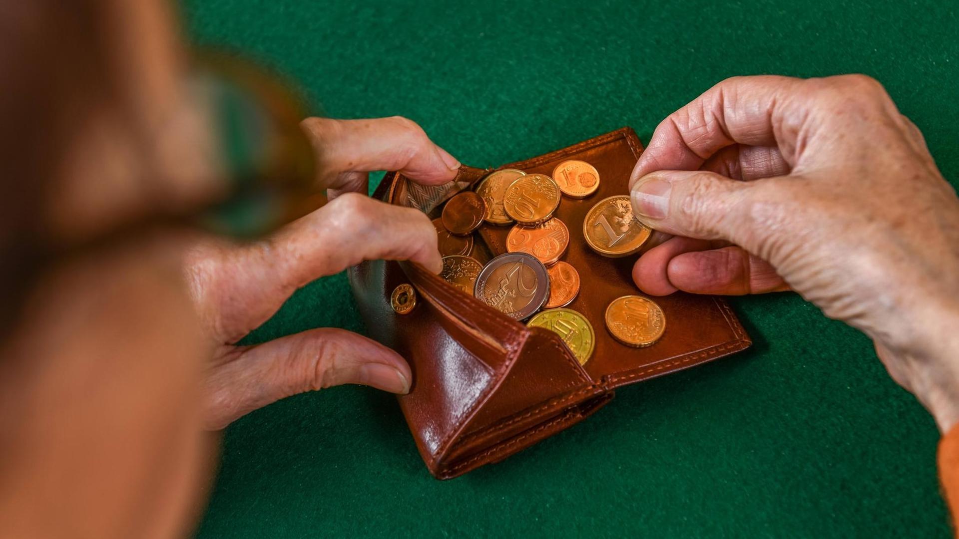Eine Frau zählt Münzen in ihrem Portemonnaie.